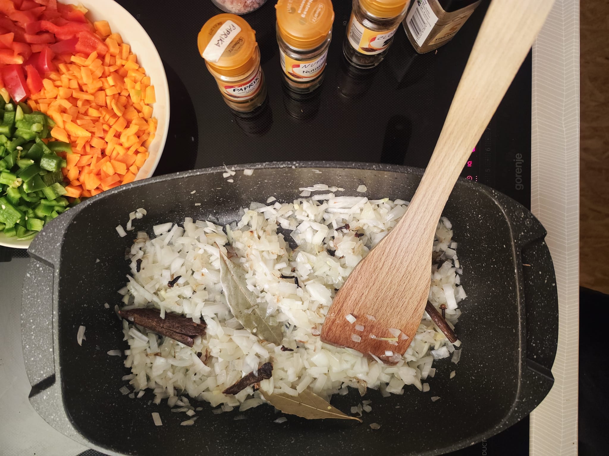 Onions sweating with whole spices — cinnamon, star anise, bay leaves, cloves