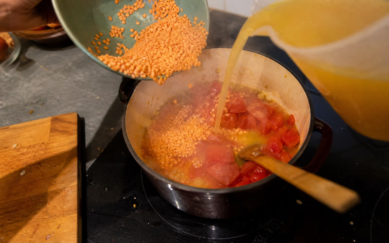 Lentils, tomatoes and stock going into the pot